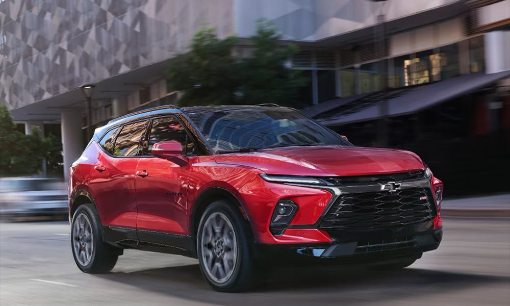 A red 2026 Chevy Blazer SUV driving down a city street