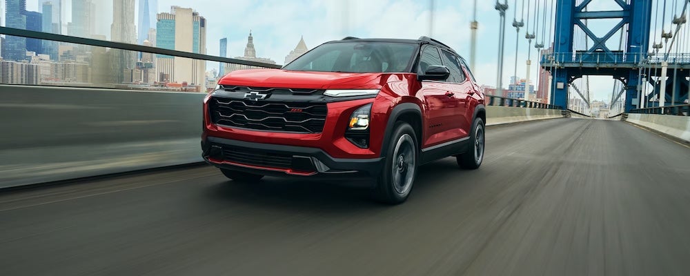 A red 2027 Chevrolet Equinox crossover driving across a bridge