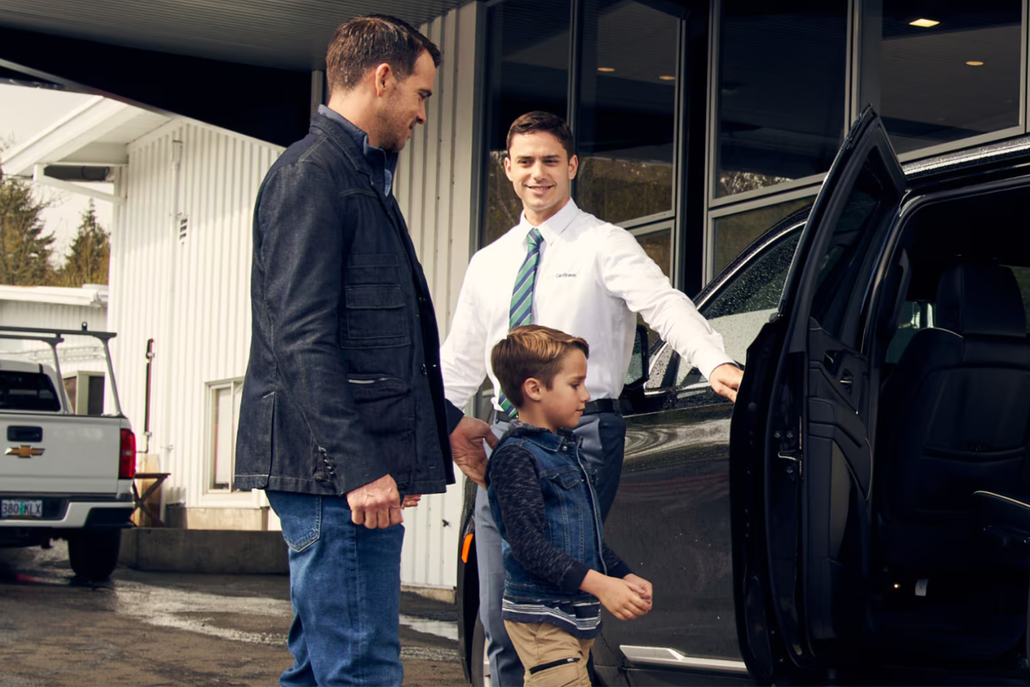 A Chevy dealership team member opening a car door for a man and small child