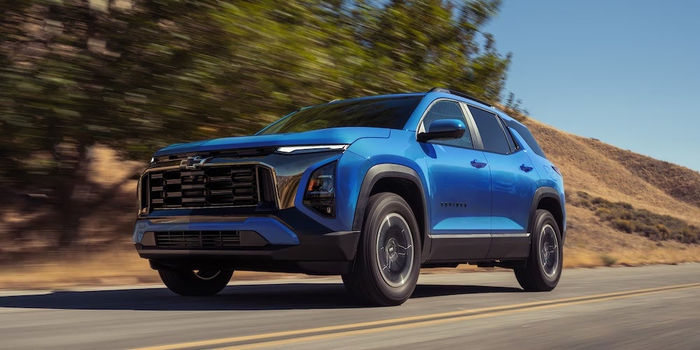 A bright blue 2027 Chevrolet Equinox SUV driving down a road