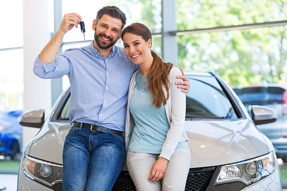 A customer is proudly displaying the key to their car in the showroom